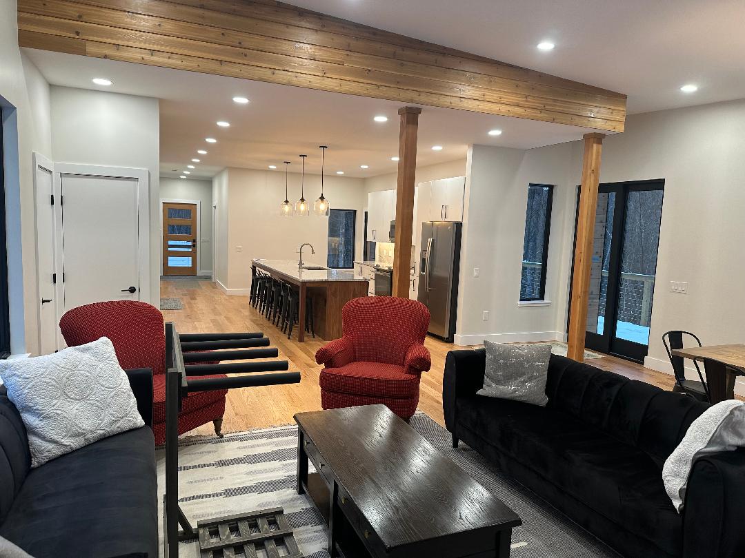 Cozy modern living room with red and black seating and a wooden ceiling beam.